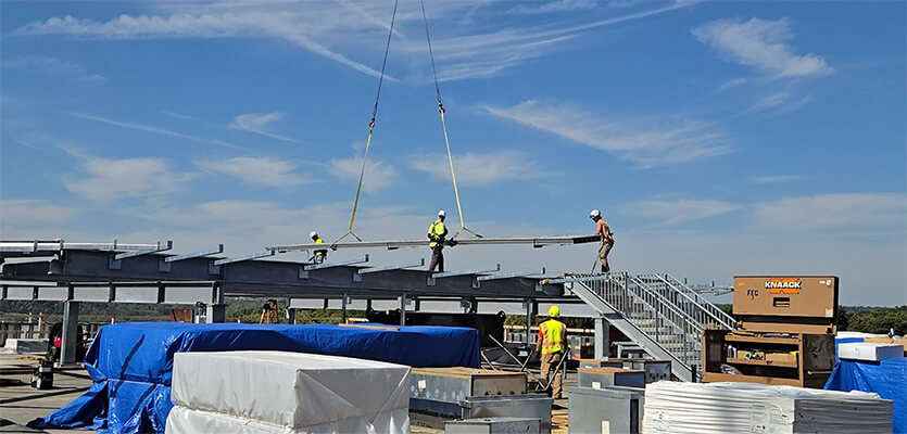 FEC heliports employees installing a large beam as part of a new helipad build on a clear beautiful day