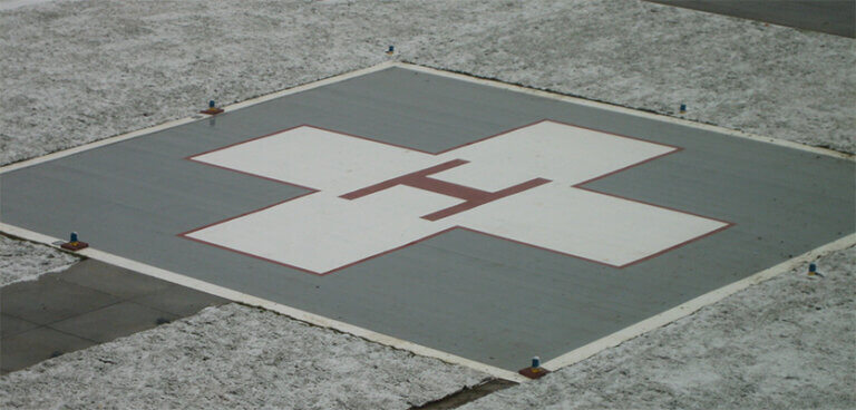 Aerial shot of a helipad landing zone on top of a building with snow surrounding it