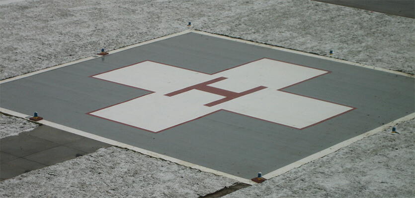 Aerial shot of a helipad landing zone on top of a building with snow surrounding it