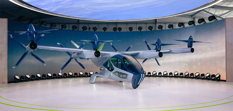 eVTOL aircraft displayed in an indoor demonstration space with multiple electric rotors and propellers.