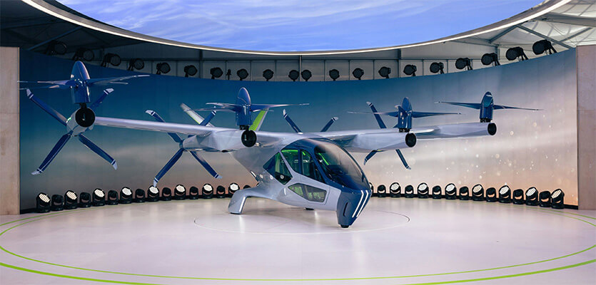 eVTOL aircraft displayed in an indoor demonstration space with multiple electric rotors and propellers.